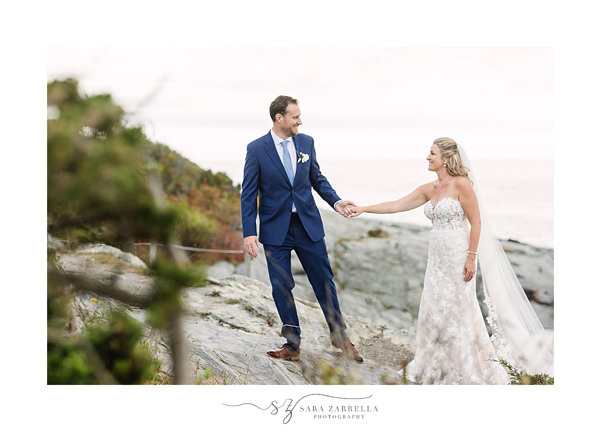 bride and groom walk up rocks by Castle Hill Lighthouse