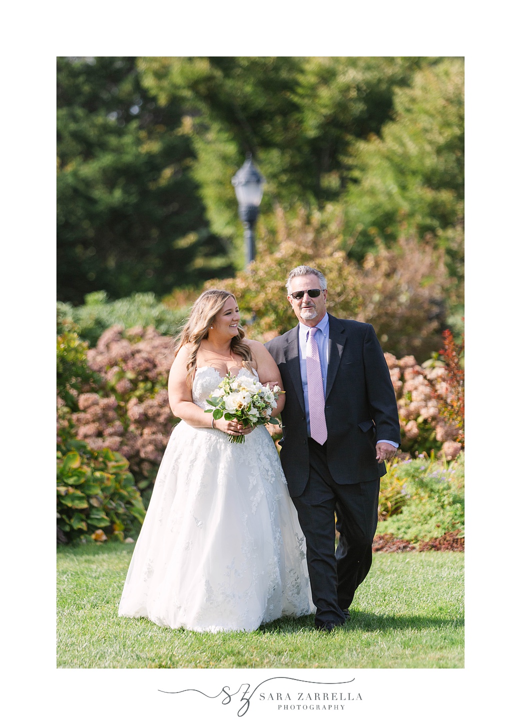bride walks down aisle with father at Chanler at Cliff Walk