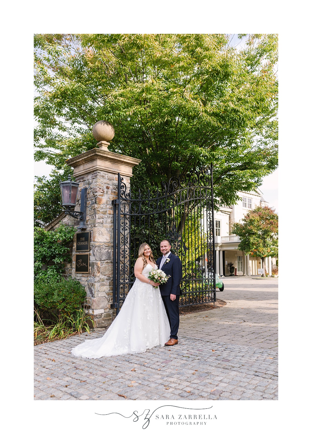 bride and groom pose by wrought iron gates in Newport RI