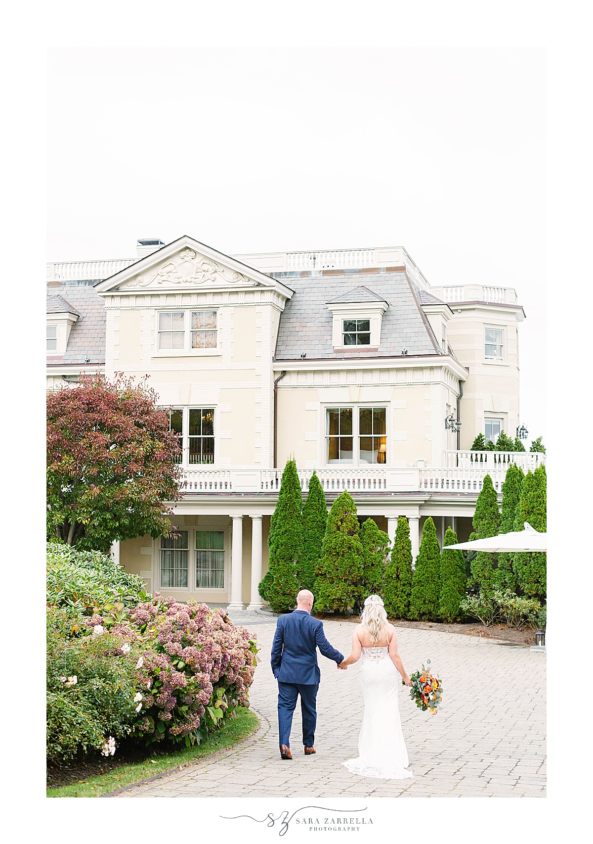 bride and groom walk up to the house at the Chanler at Cliff Walk