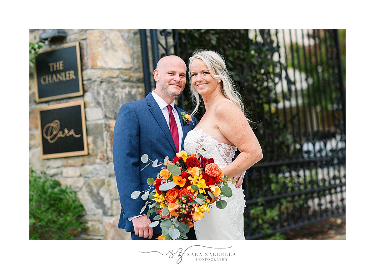 bride and groom pose together by wrought iron gates
