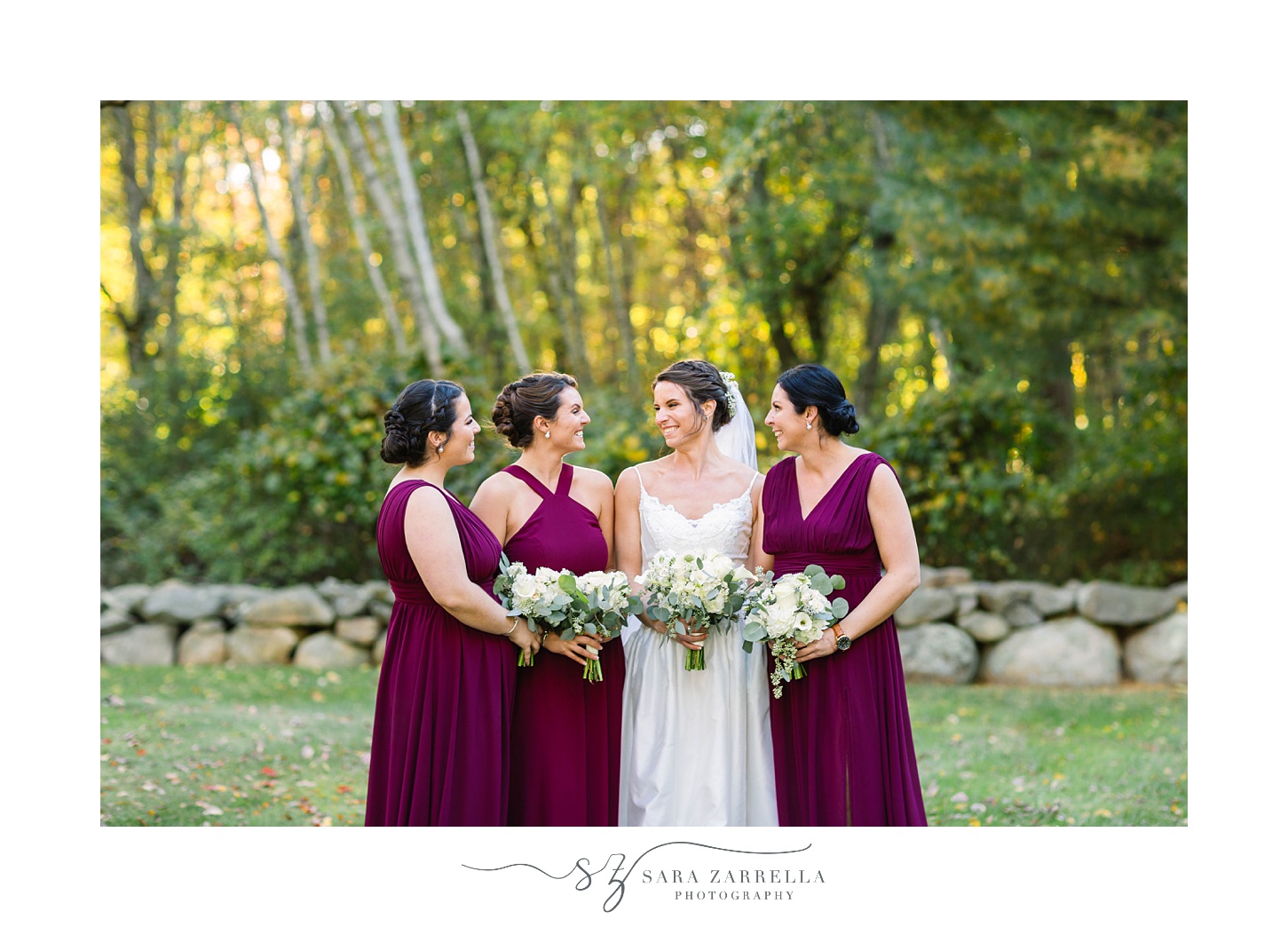 bride and bridesmaids pose by stone wall at Gerald's Farm