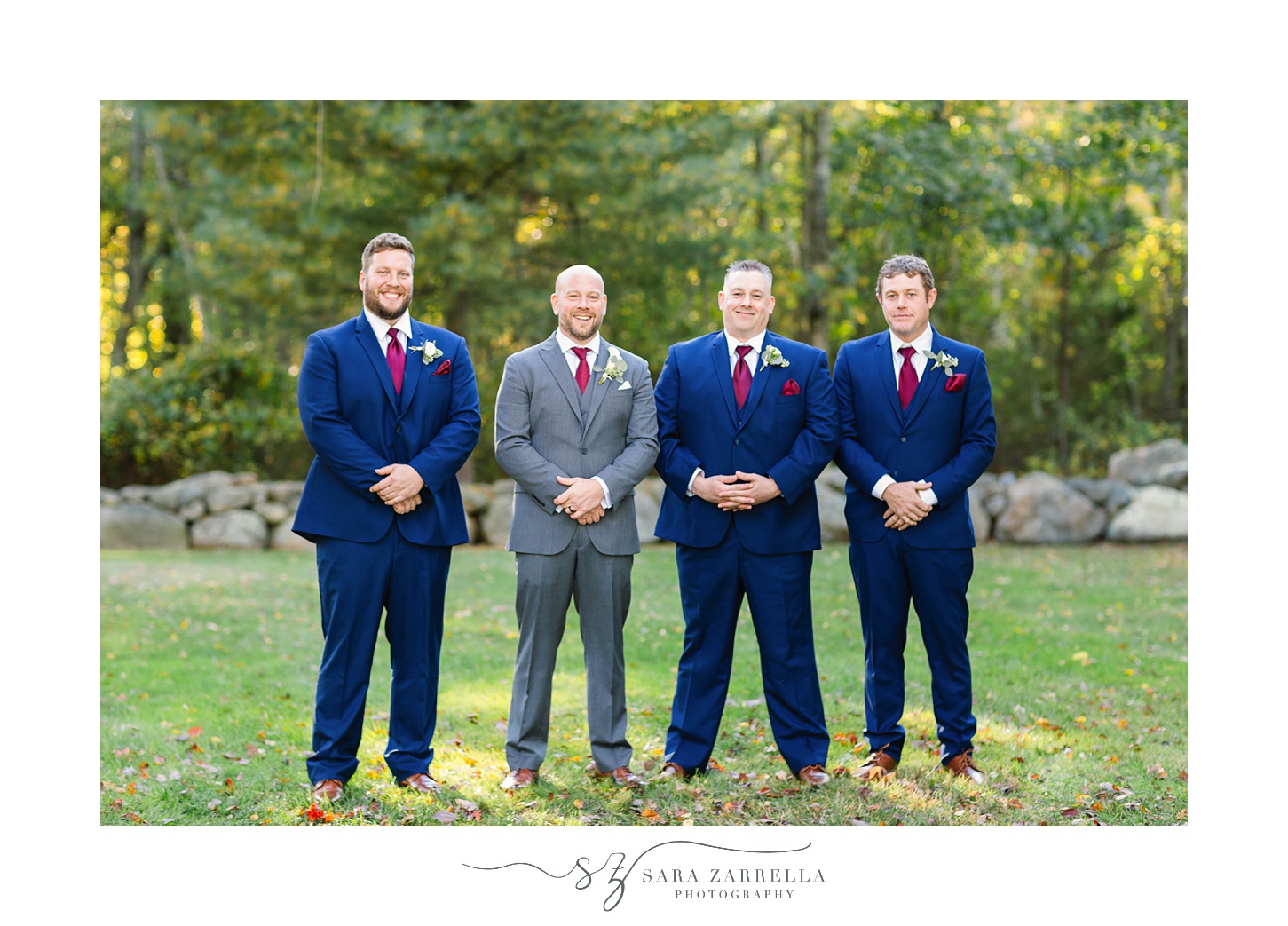 groomsmen in navy suits pose with groom in grey suit at Gerald's Farm