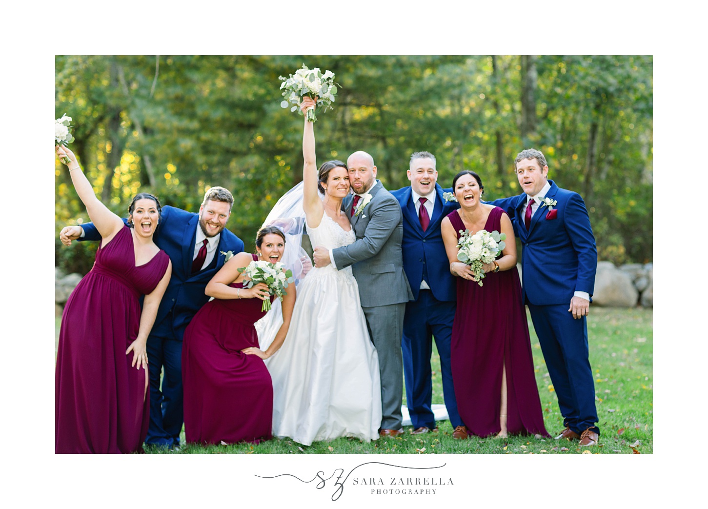 bride and groom pose with bridal party in burgundy gowns and navy suits