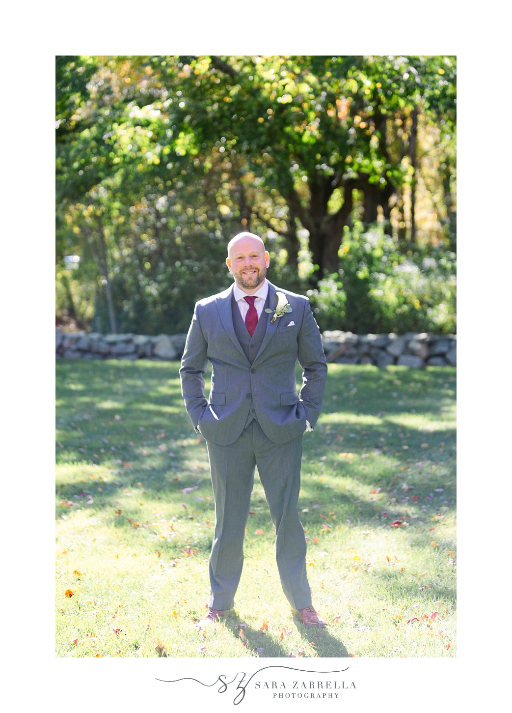 groom in grey suit poses in grass