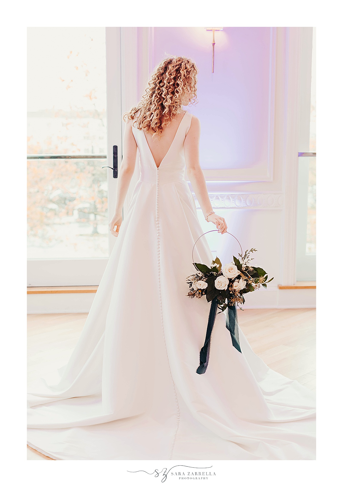 bride holds floral hoop behind back during modern winter wedding