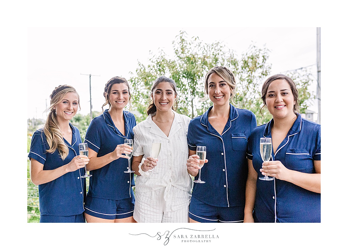 bridesmaids in matching navy pajamas hold champagne glasses