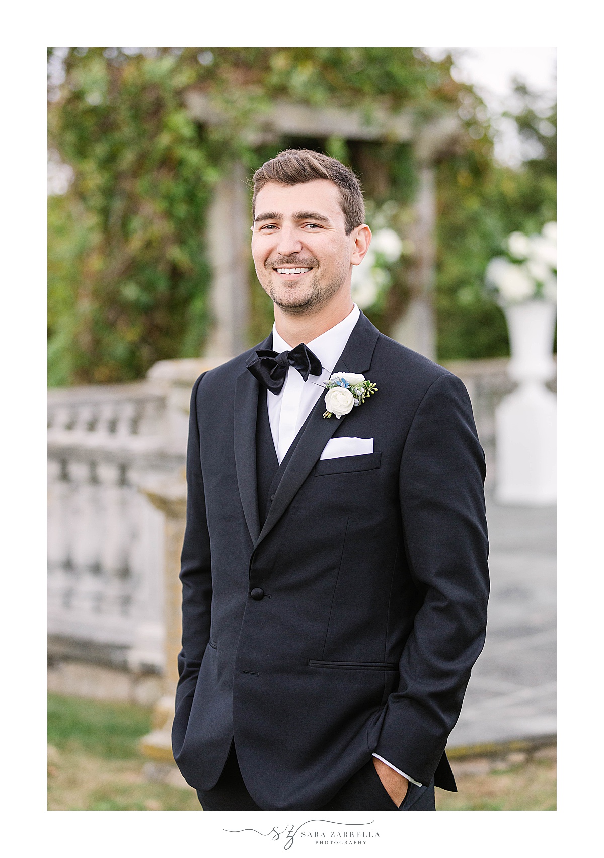 groom poses in traditional black tux before Castle Hill Inn microwedding