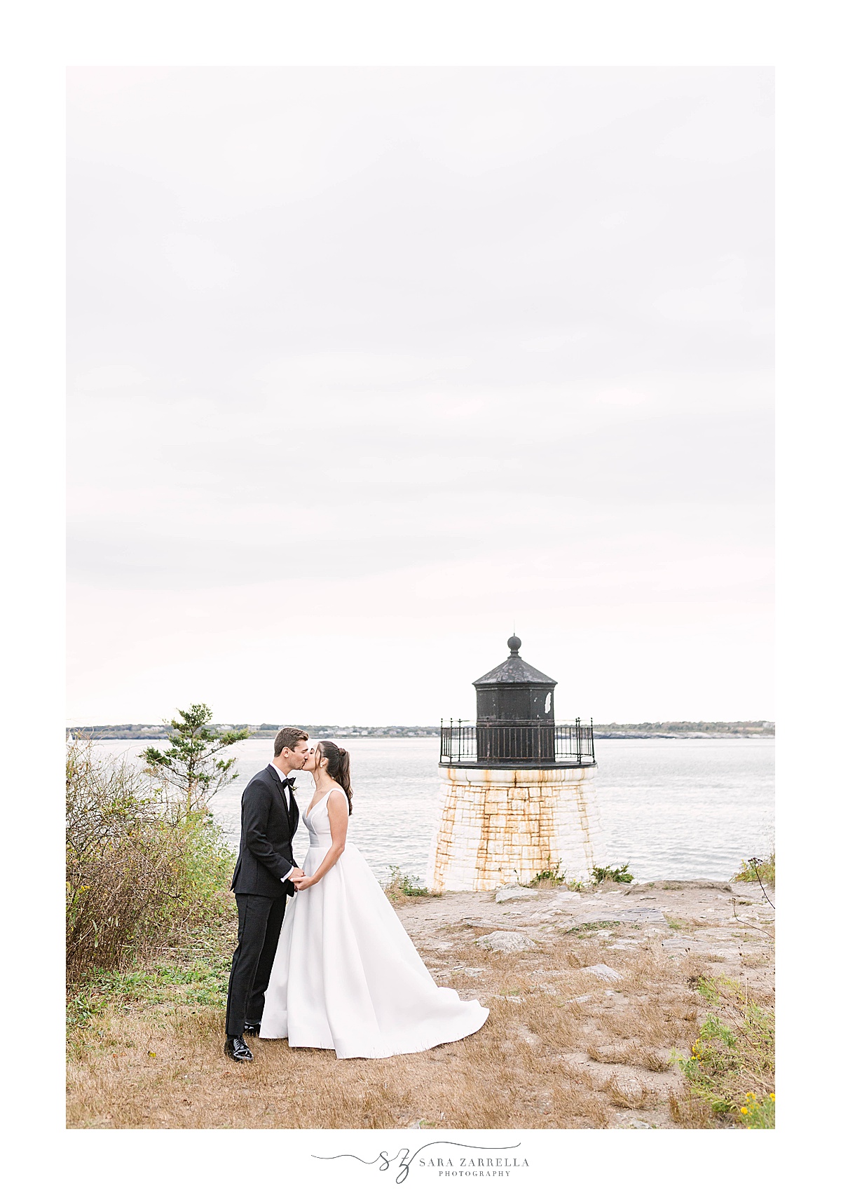 bride and groom pose by Castle Hill Inn lighthouse 