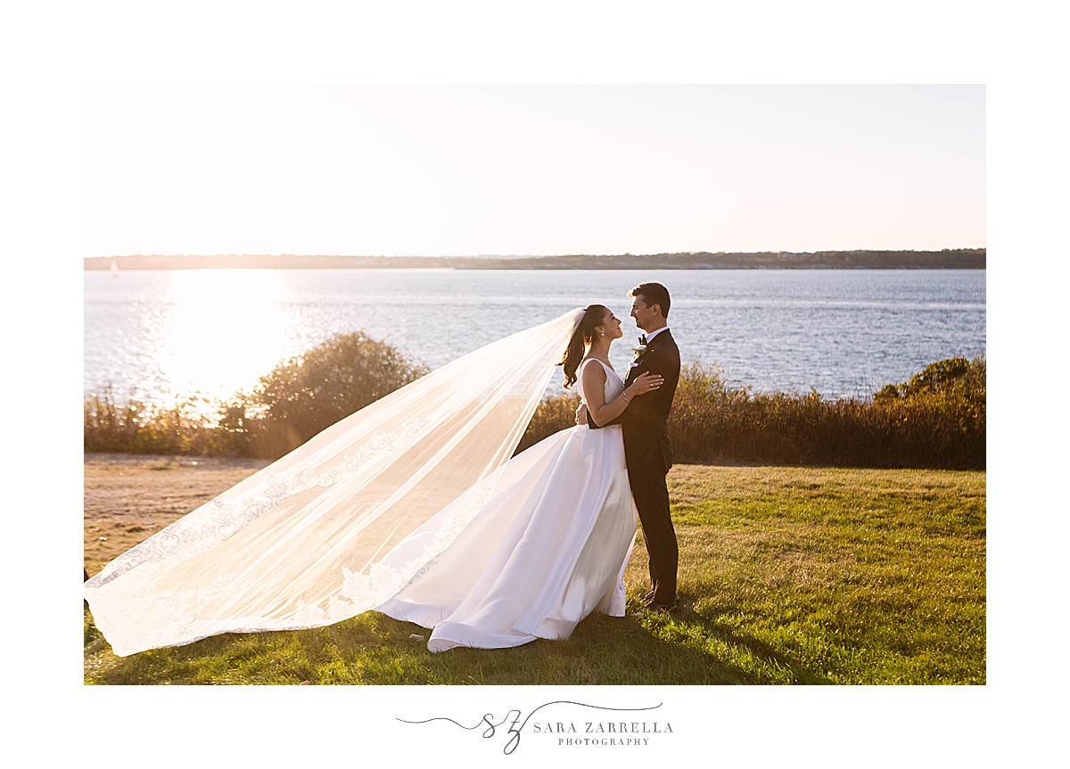 bride and groom pose along Newport RI waterfront at sunset
