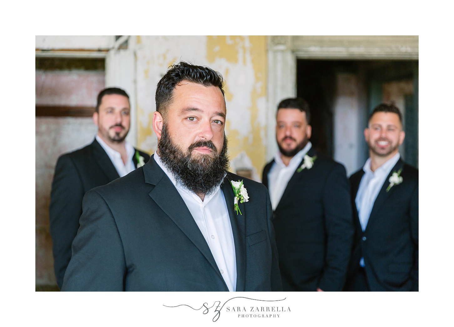 groom poses with groomsmen inside Fort Adams