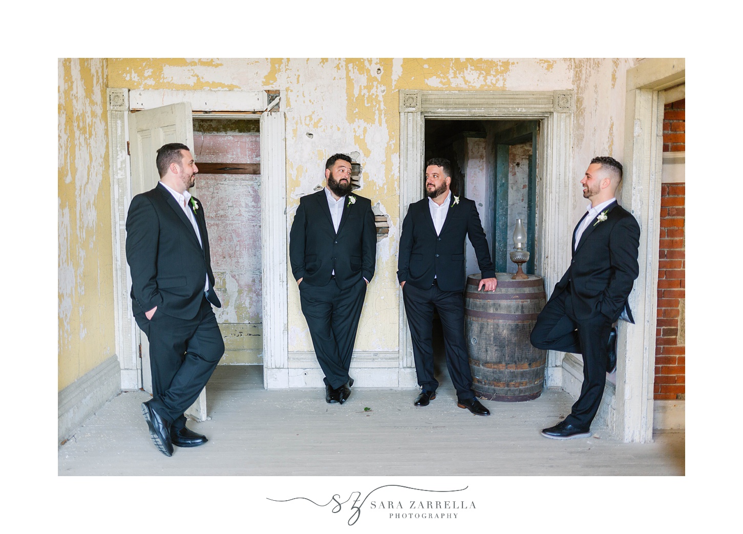 groom and groomsmen lean against doorways of Fort Adams
