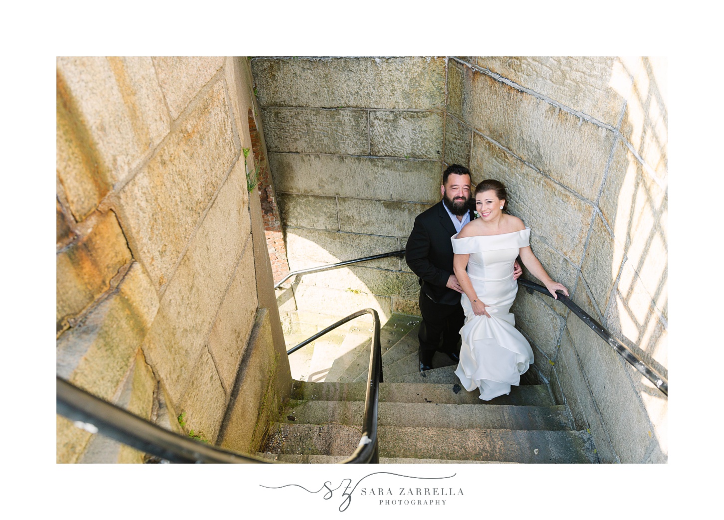 newlyweds pose in staircase of Fort Adams