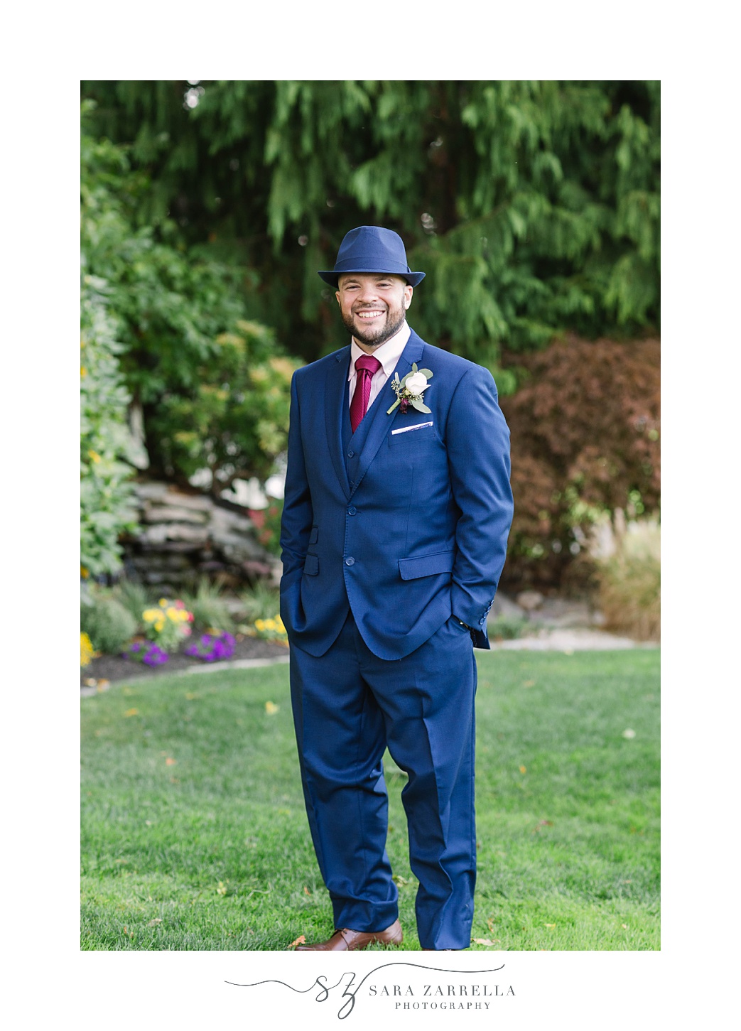 groom in navy suit with fedora poses for RI wedding photos