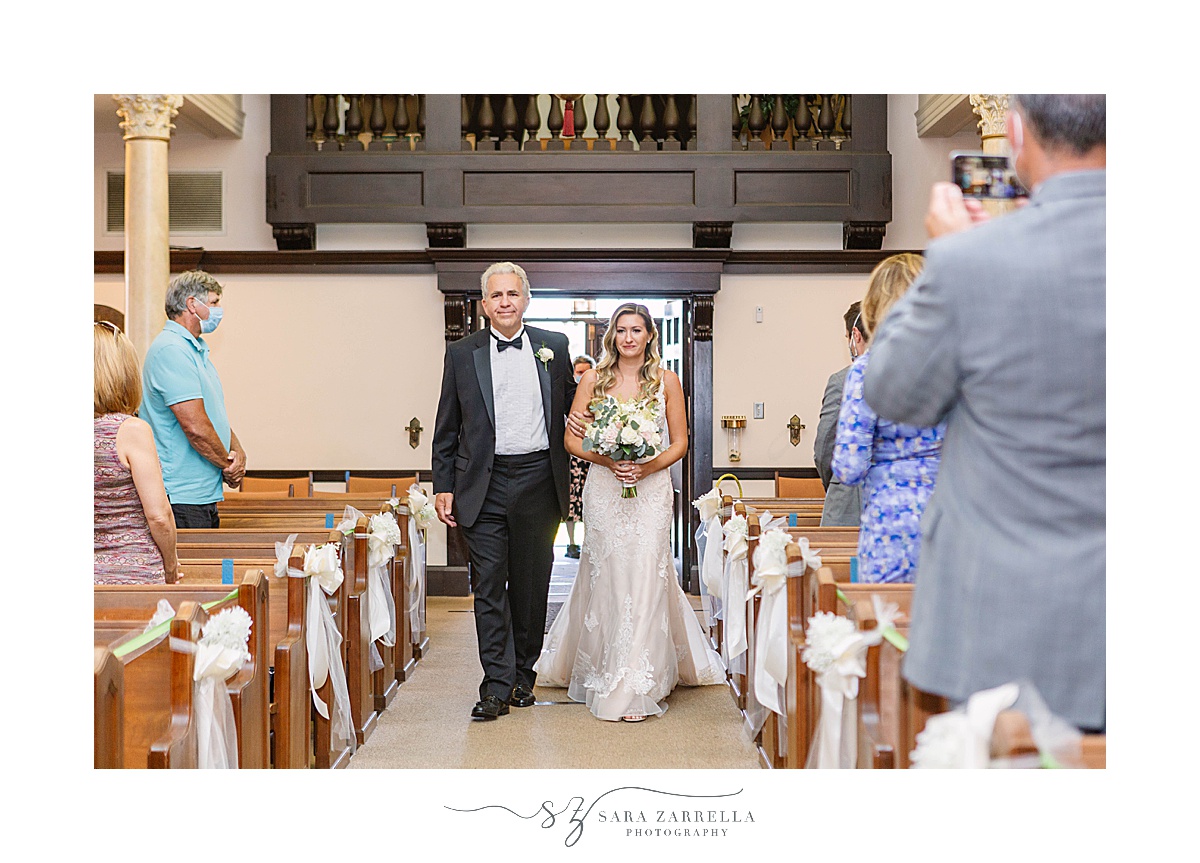 bride walks down aisle with father during traditional church wedding in Newport RI