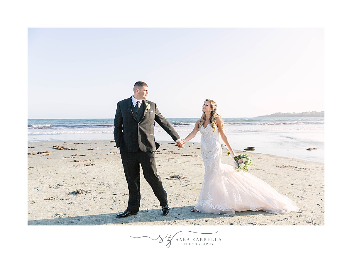 bride and groom walk along Newport RI beach