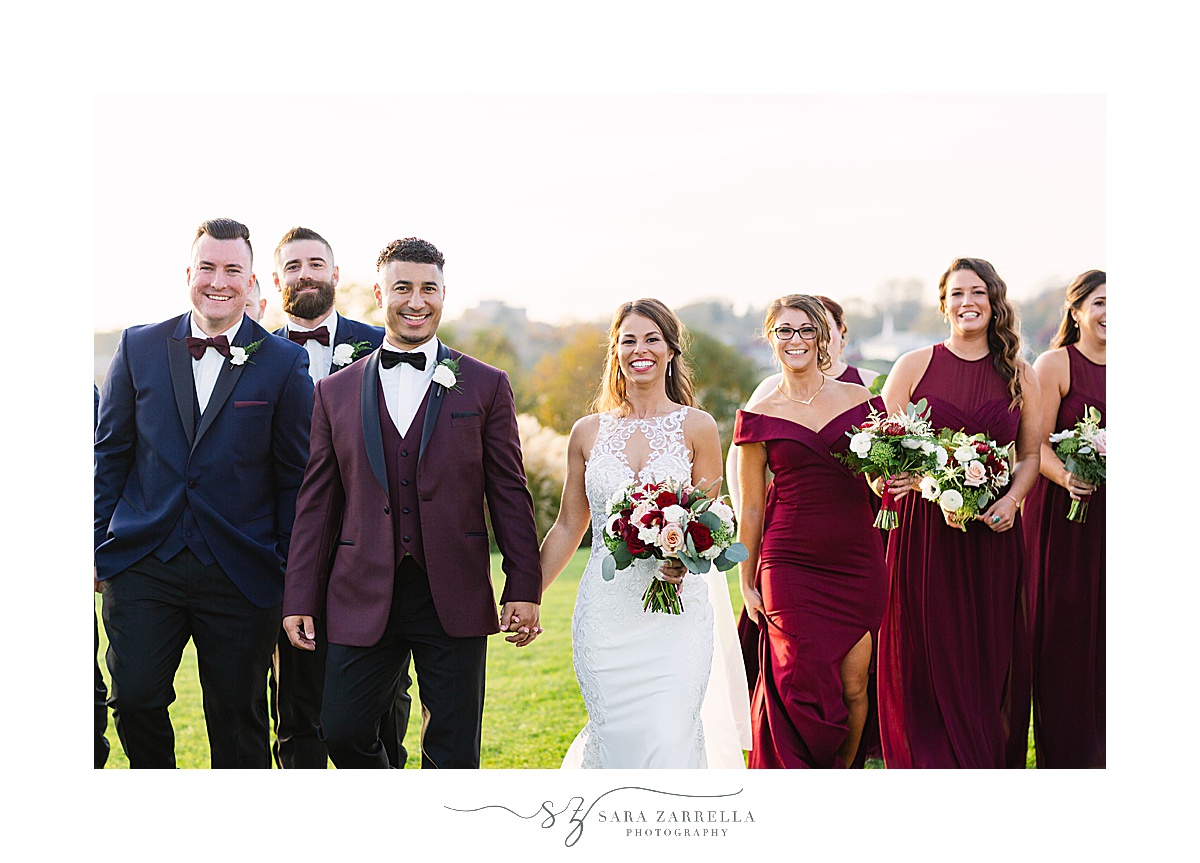 bride and groom hold hands walking with bridal party