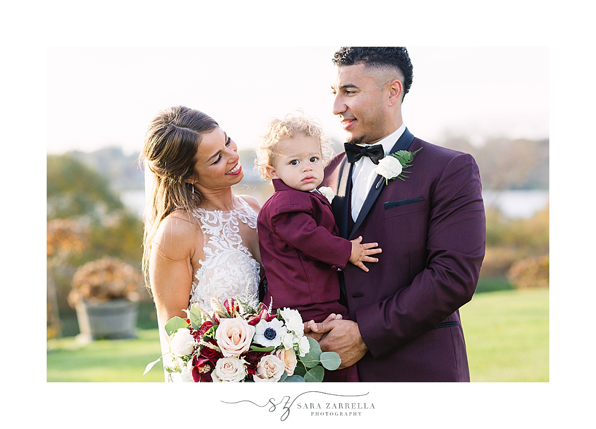 newlyweds pose with son in red jacket on wedding day