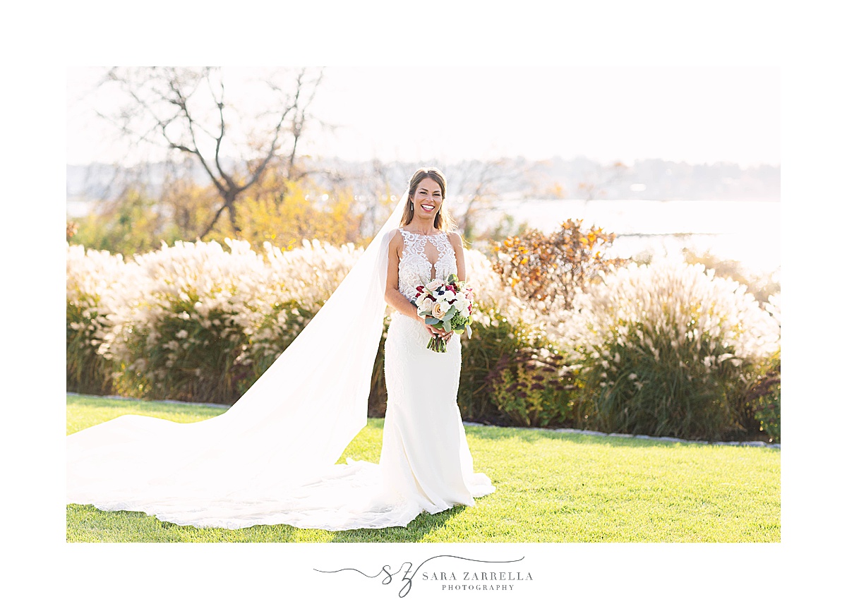 bride holds fall bouquet and poses by waterfront in Middletown RI