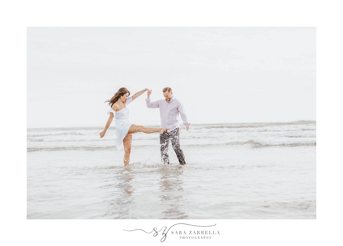 couple splashes in water during engagement photos