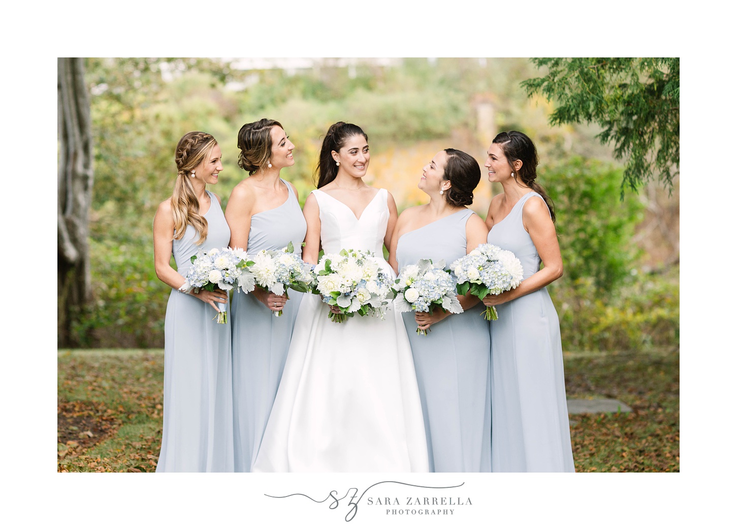 bride laughs with bridesmaids in pale blue dresses during RI wedding