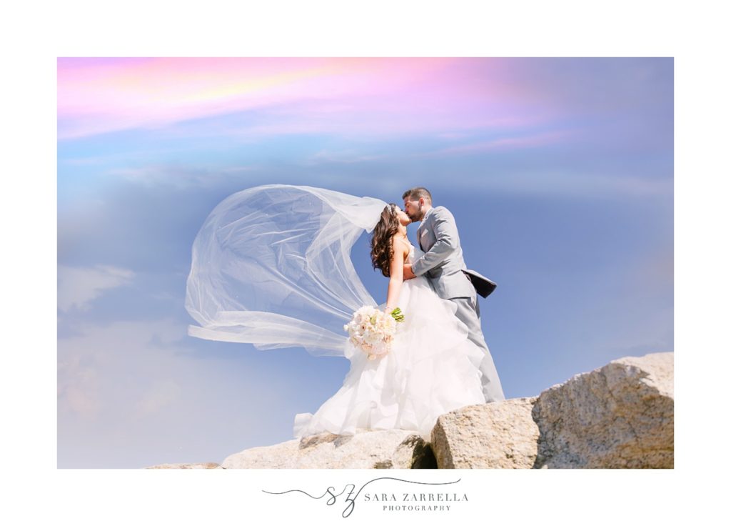 bride and groom kiss on rocks in Rhode Island on wedding day with Sara Zarrella Photography