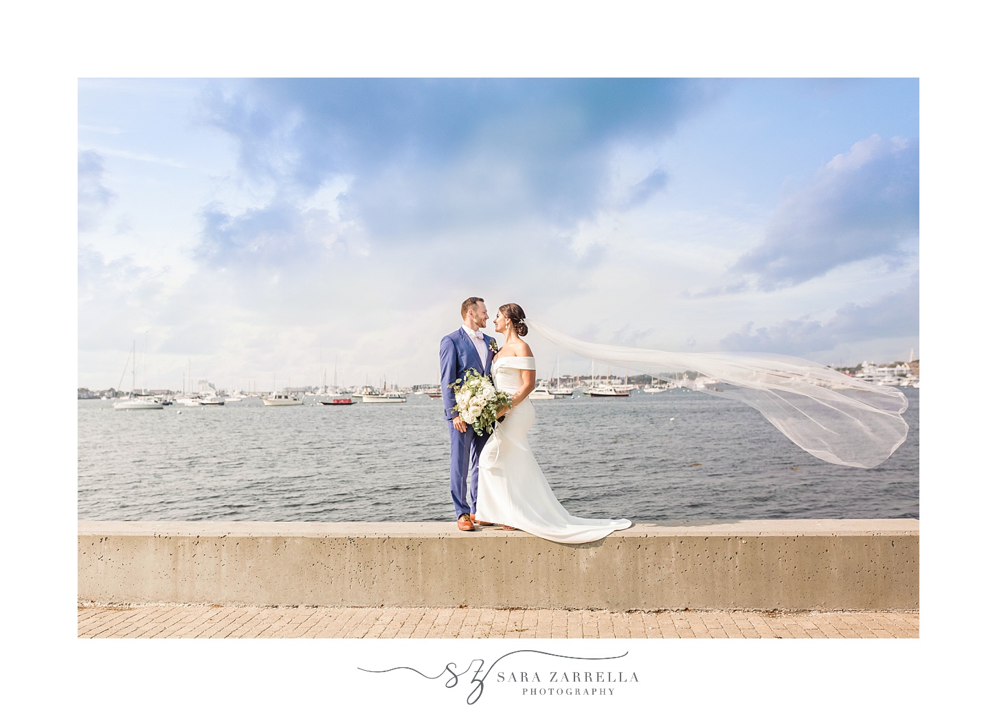 couple poses on wall in Rhode Island during wedding portraits 