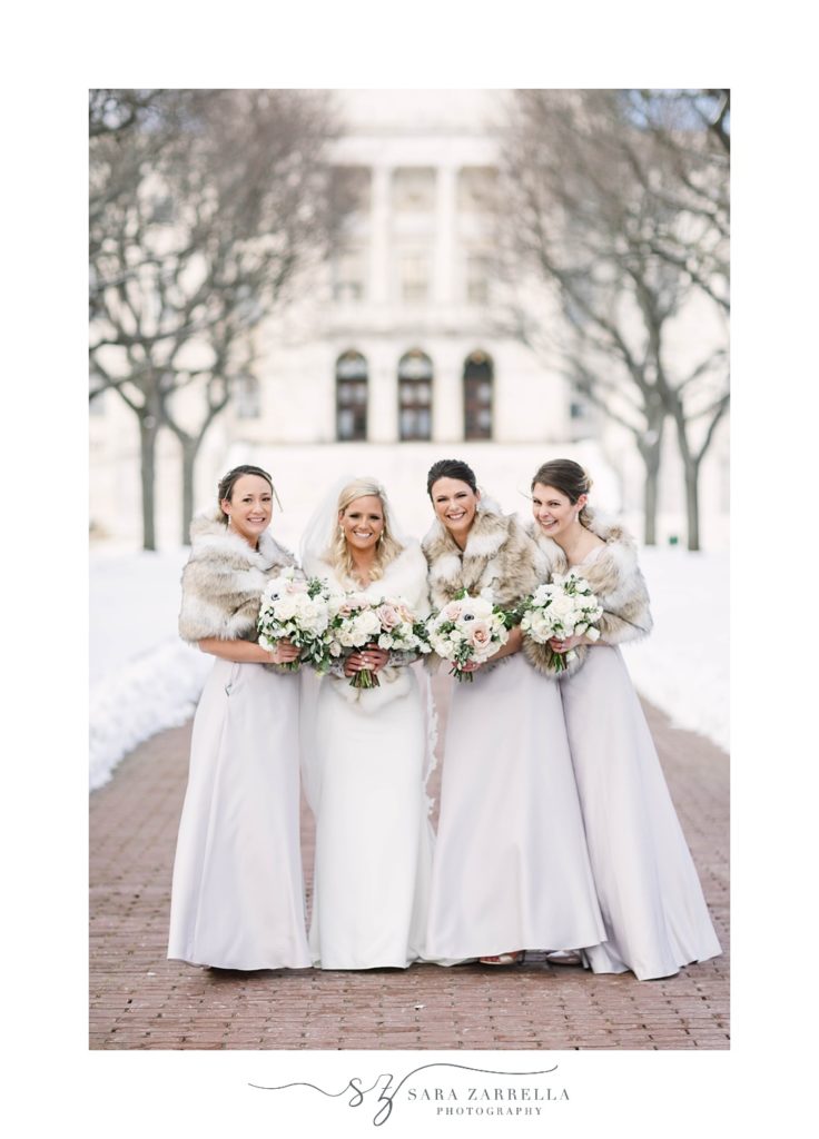 bride laughs with bridesmaids in pale gowns with furs