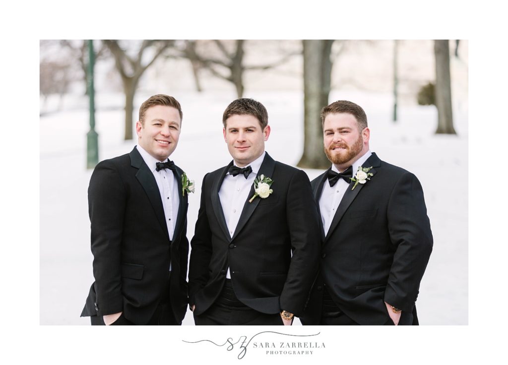 groom poses with two groomsmen in snow