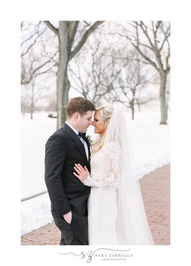 bride and groom nuzzle noses in the snow during winter RI wedding photos