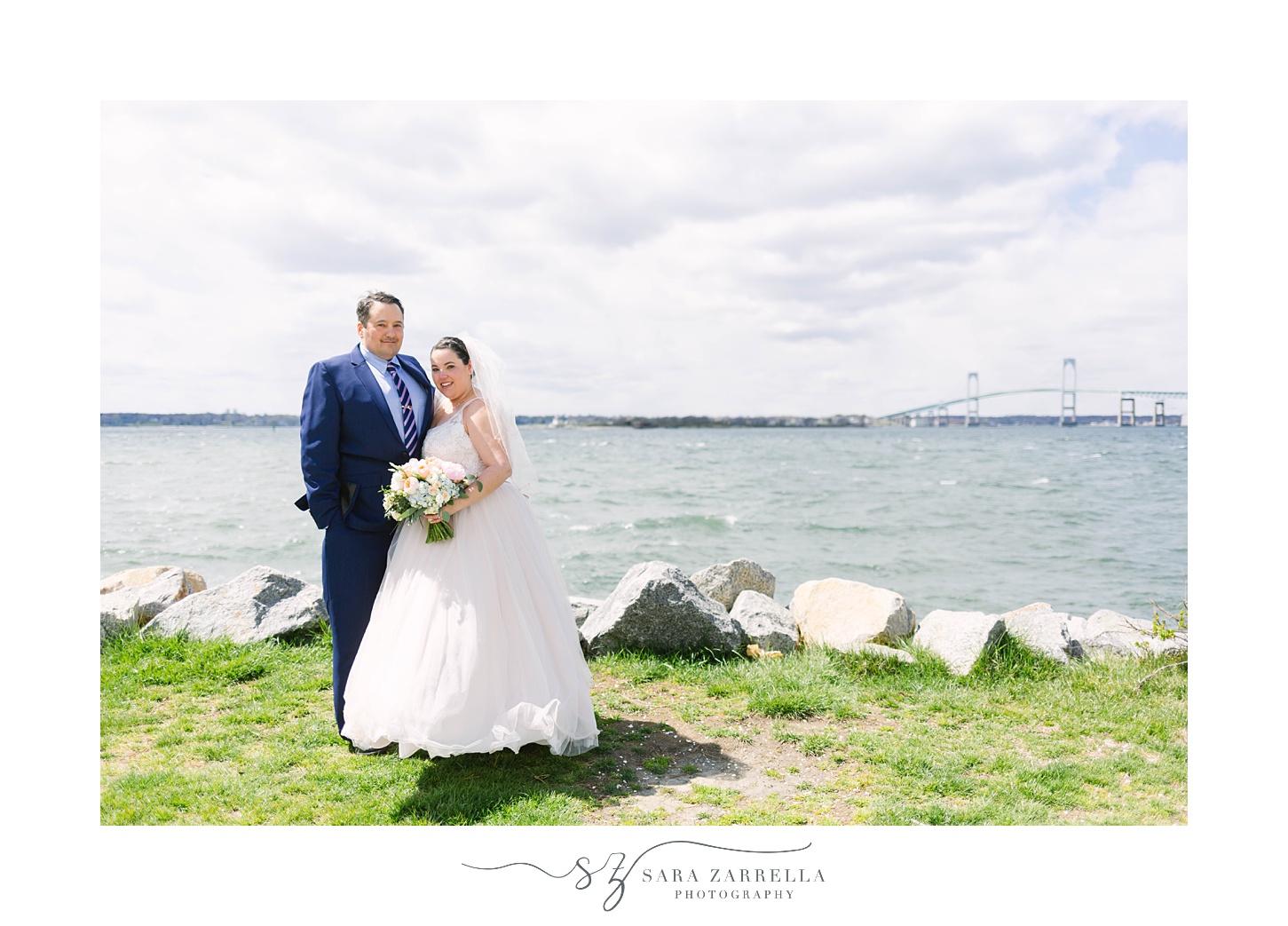 bride and groom pose in front of Newport waterfront