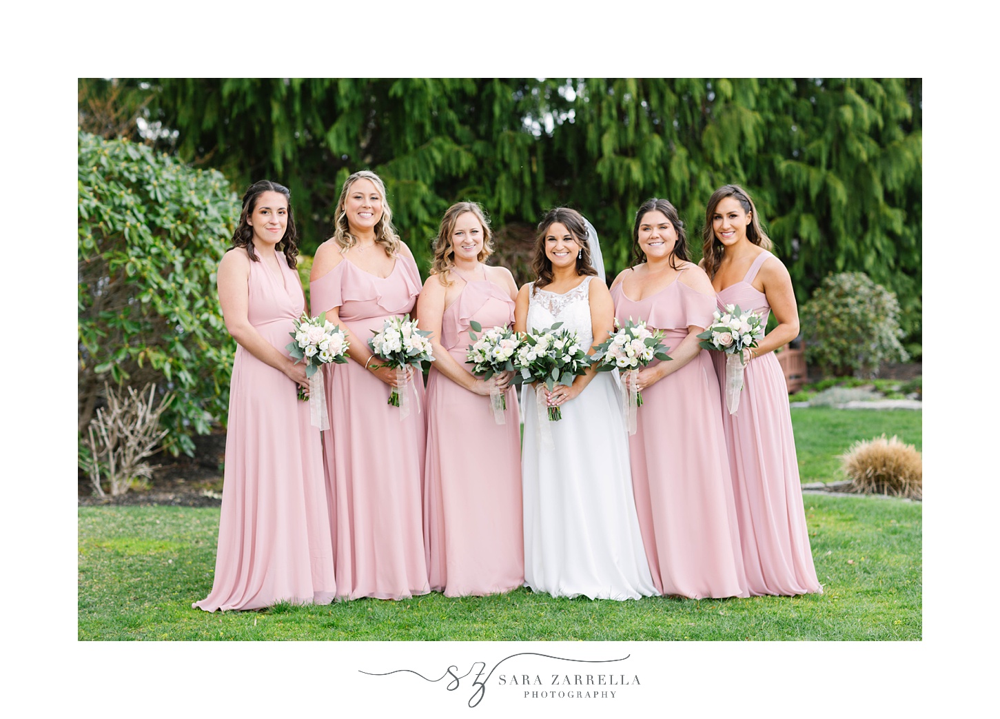 bride poses with bridesmaids in pink gowns