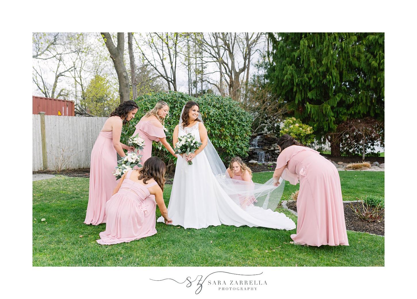 bridesmaids in pale pink adjust bride's dress