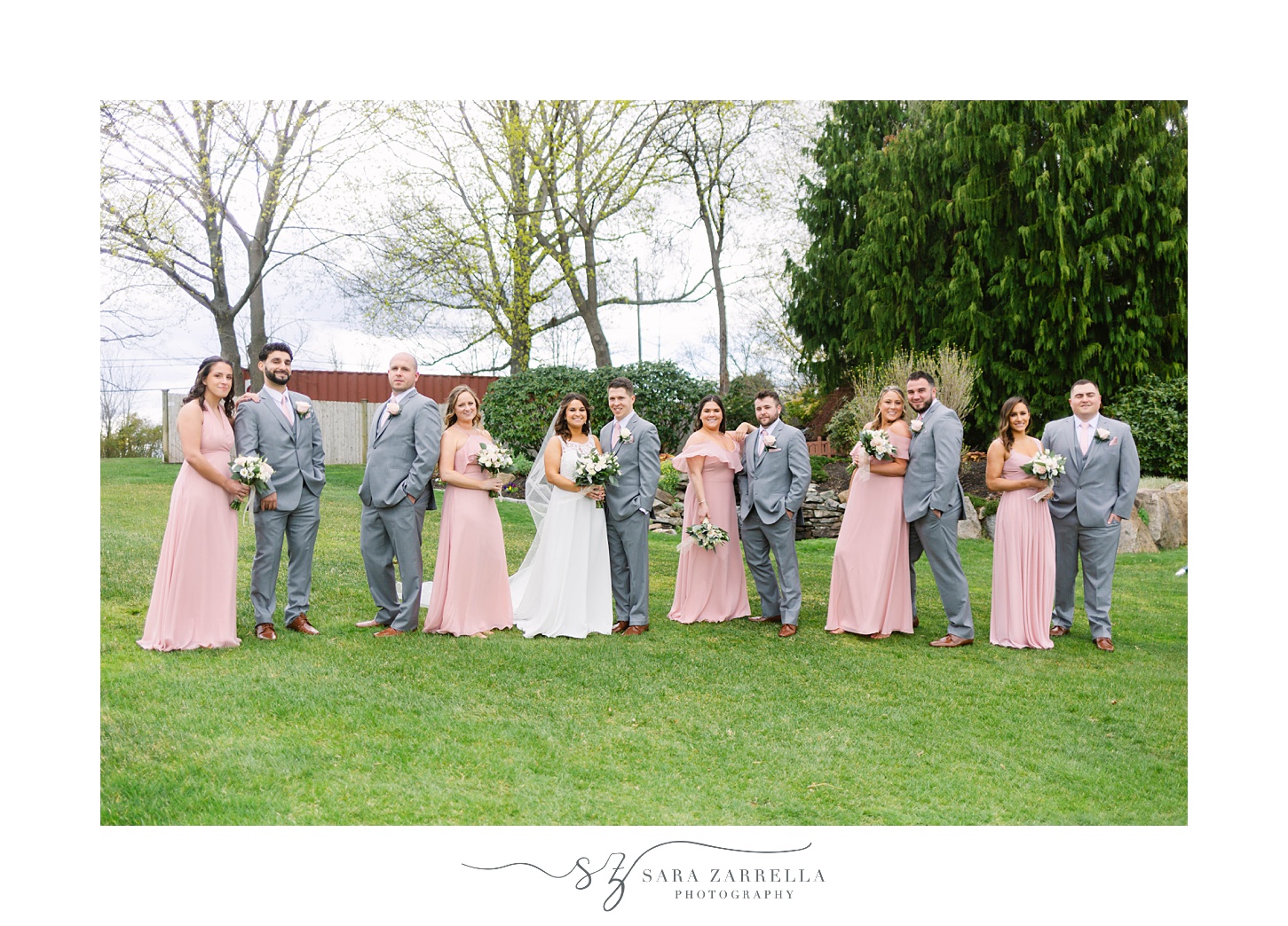 bride and groom pose with bridal party in pastel outfits 