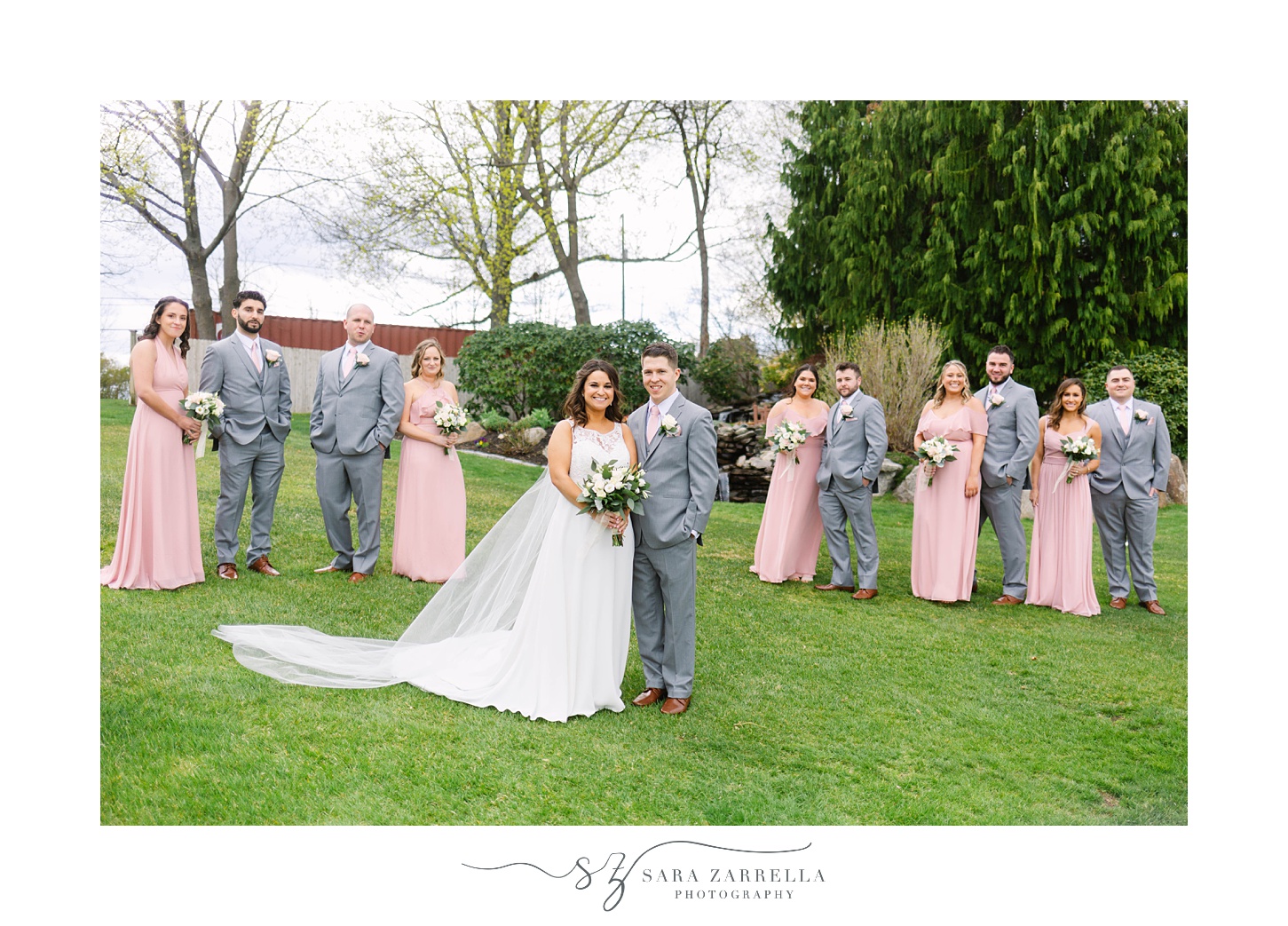 bride and groom stand with bridal party in grey and pink attire 