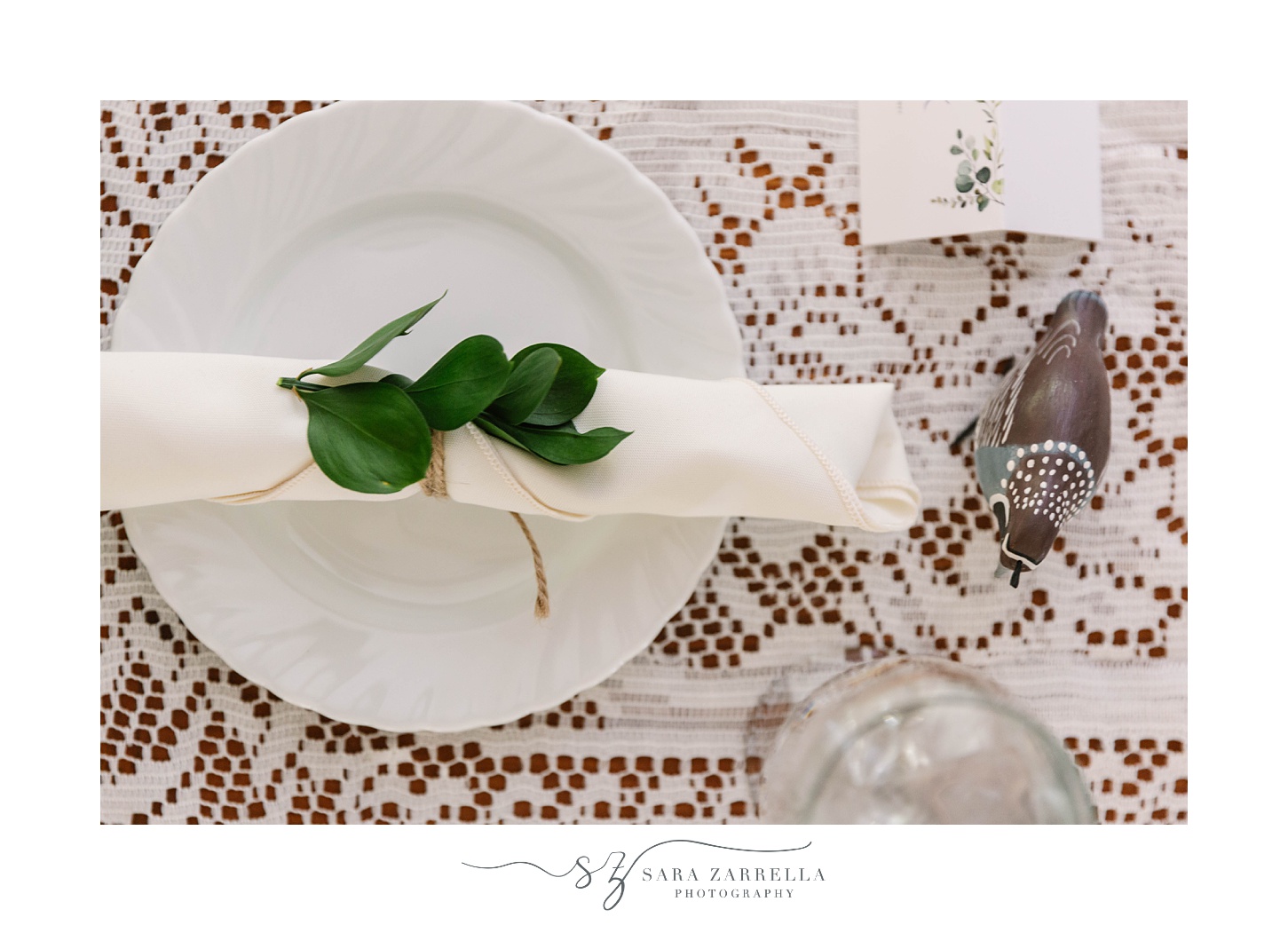 place setting with white napkin and green leaves