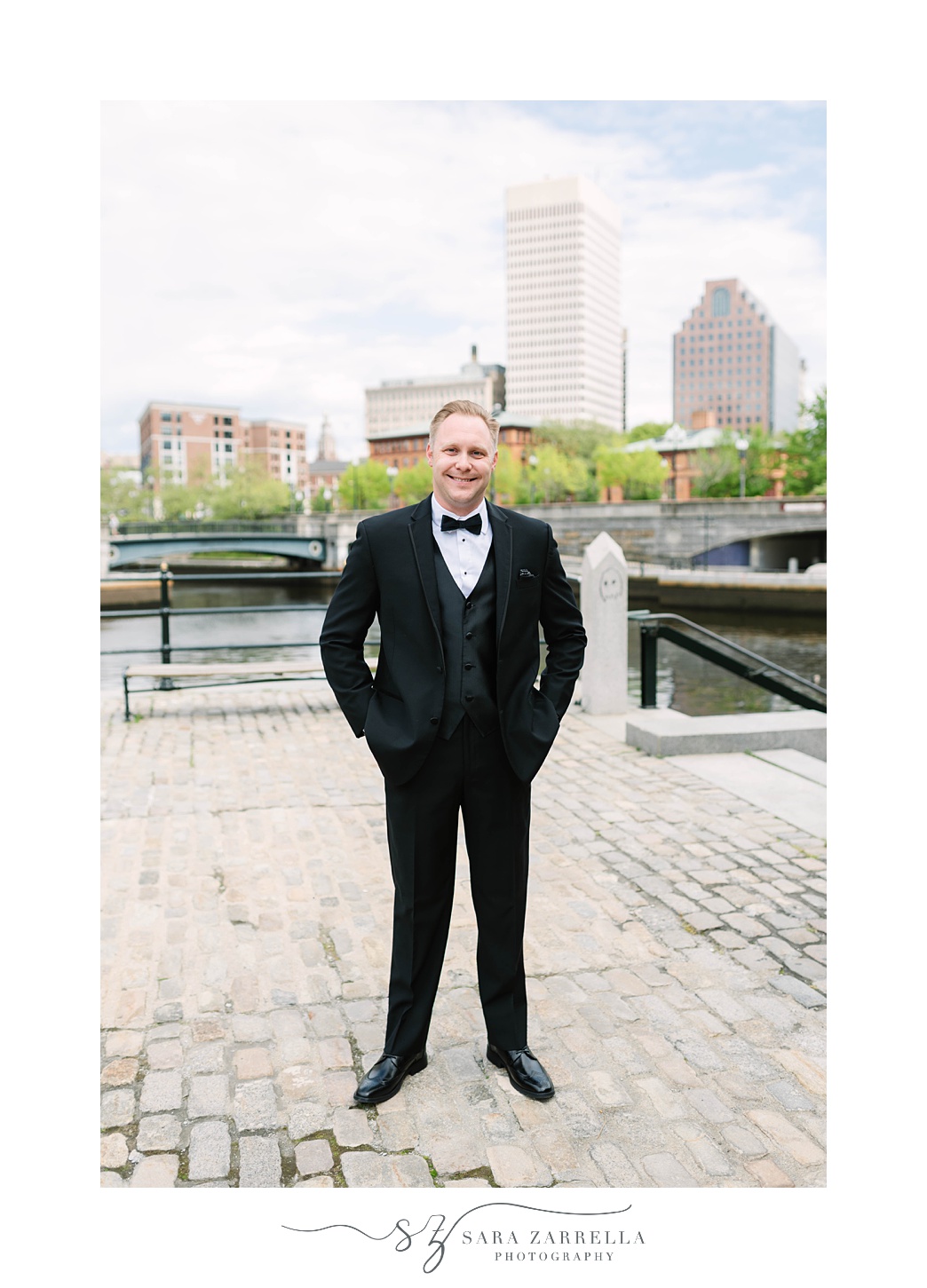groom poses with hands in pockets with Providence RI behind him