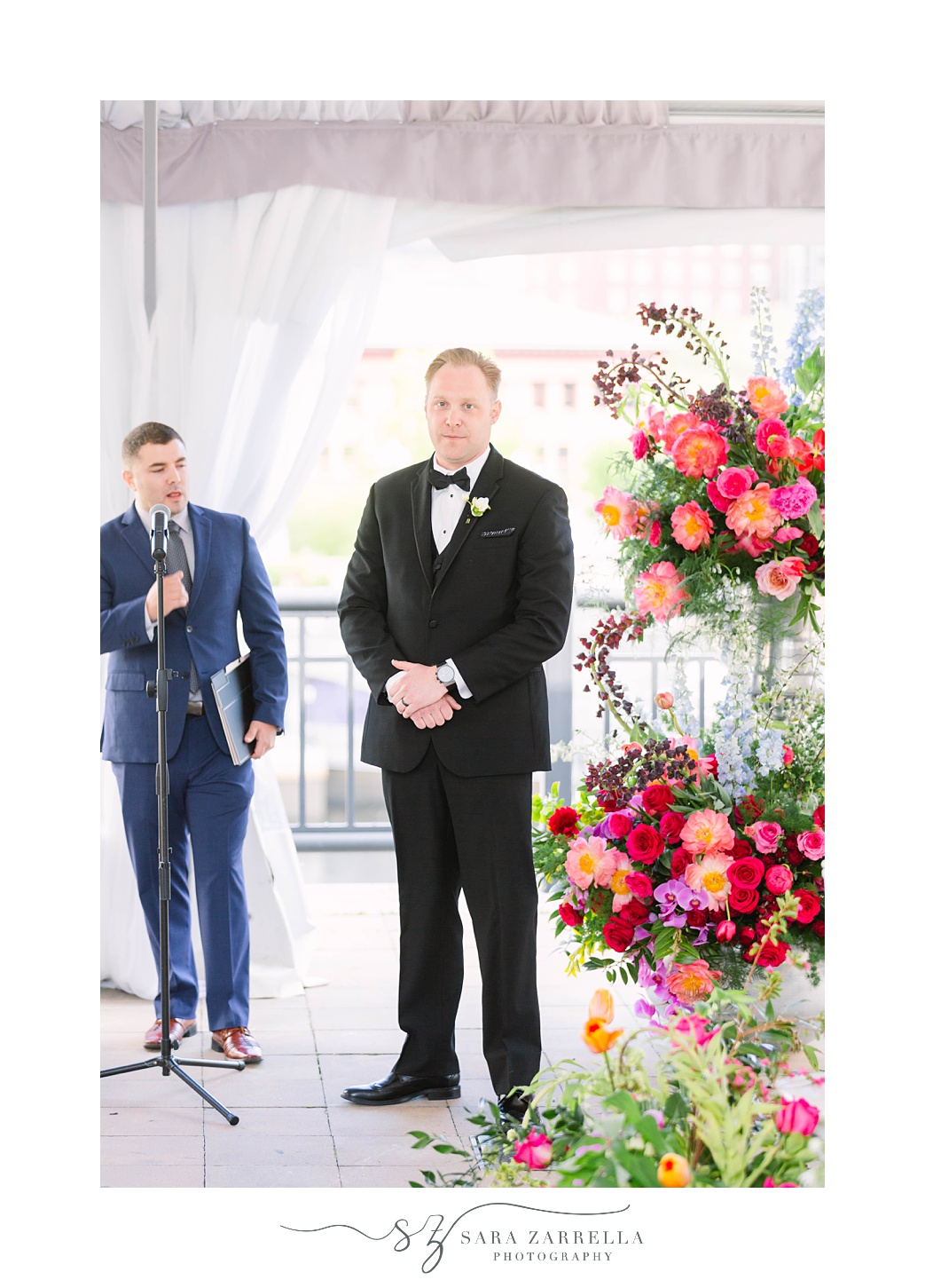 groom stands at alter by floral display in Skyline at Waterplace
