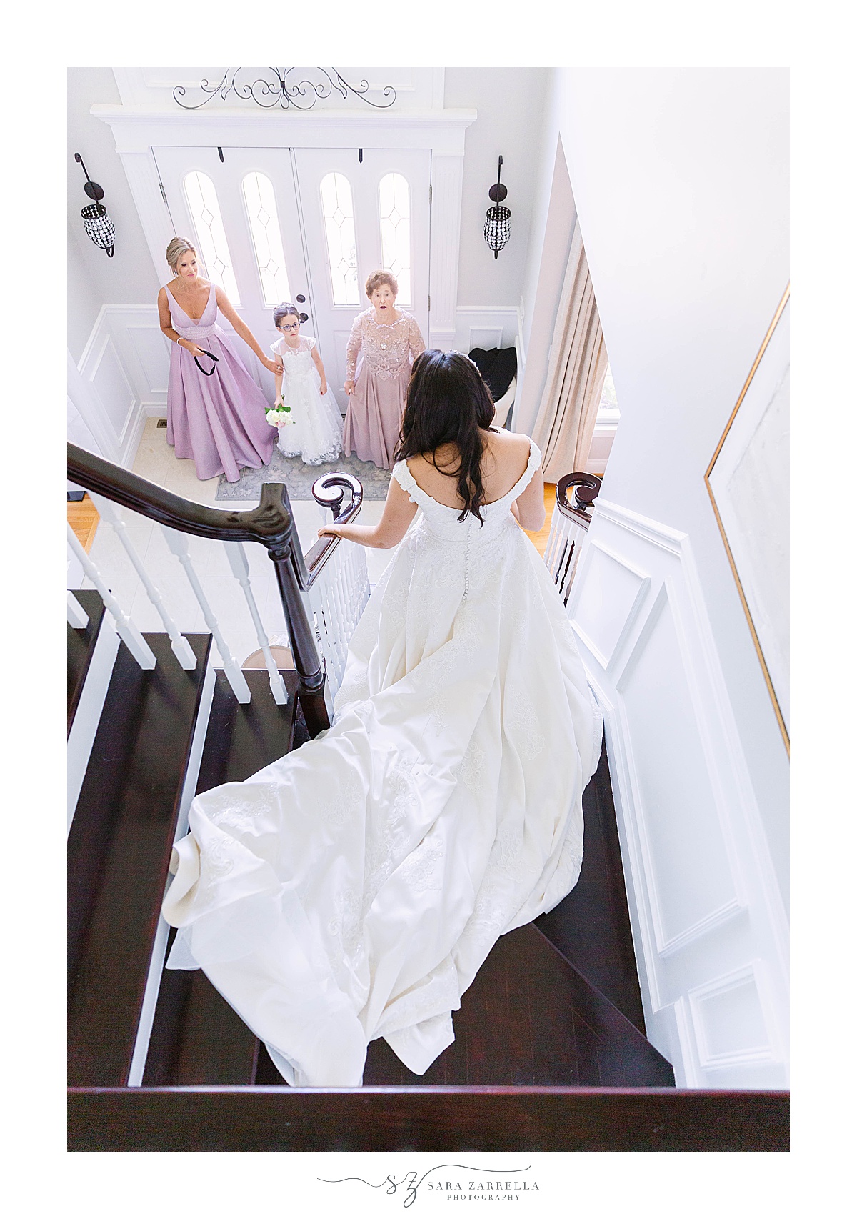 bride walks down steps at home to show mom and grandmother wedding gown