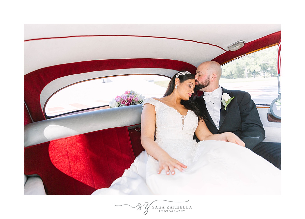 groom kisses bride in back of Rolls Royce
