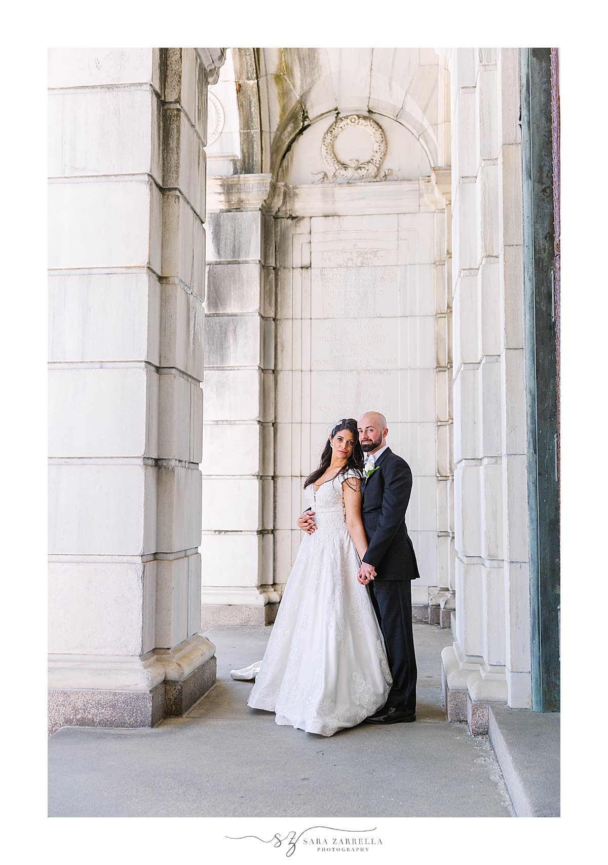 bride and groom pose in walkway of State House