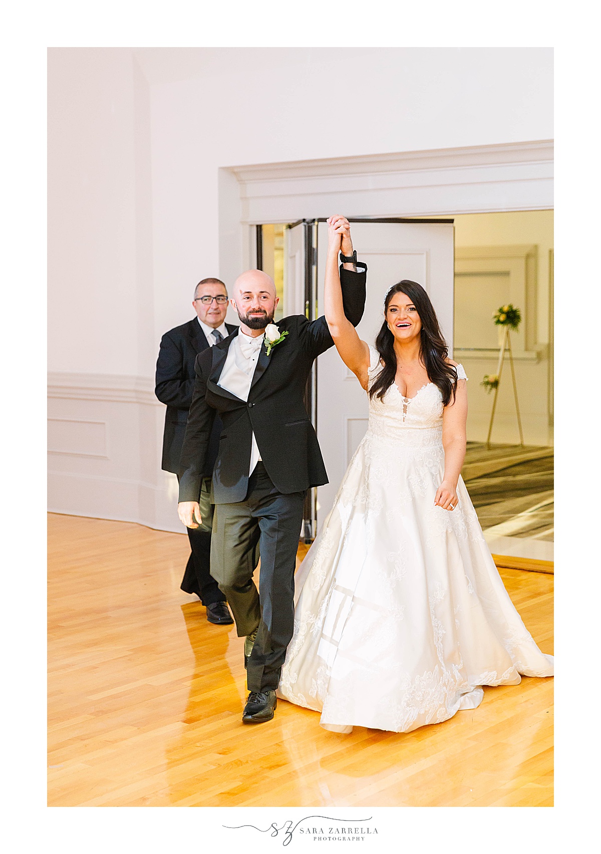 bride and groom walk into wedding reception holding hands cheering