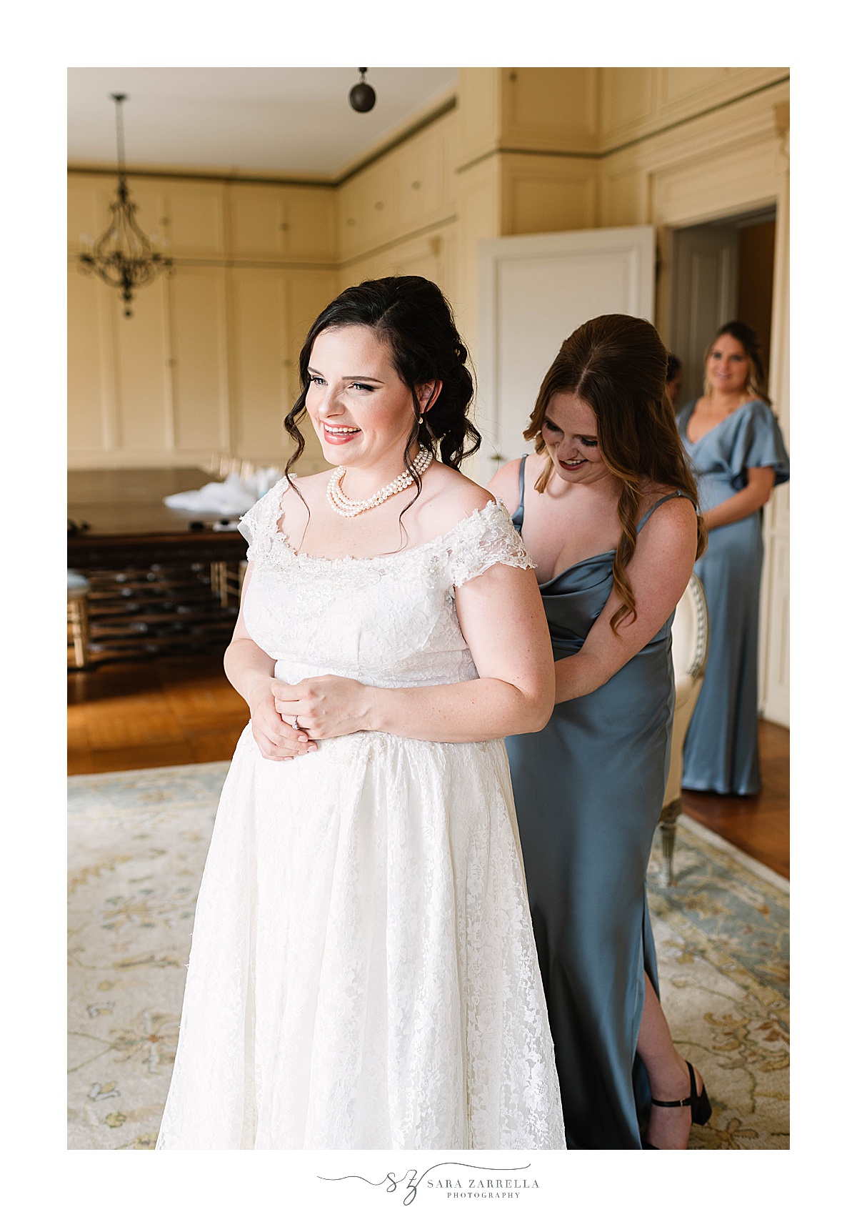 bridesmaid helps bride with wedding gown
