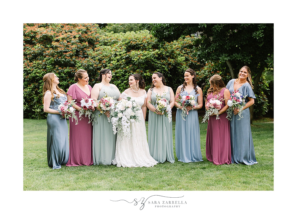 bride walks with bridesmaids in pink, blue and green gowns