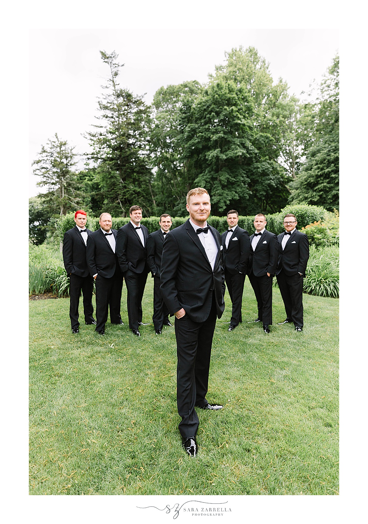 groom poses in front of groomsmen 