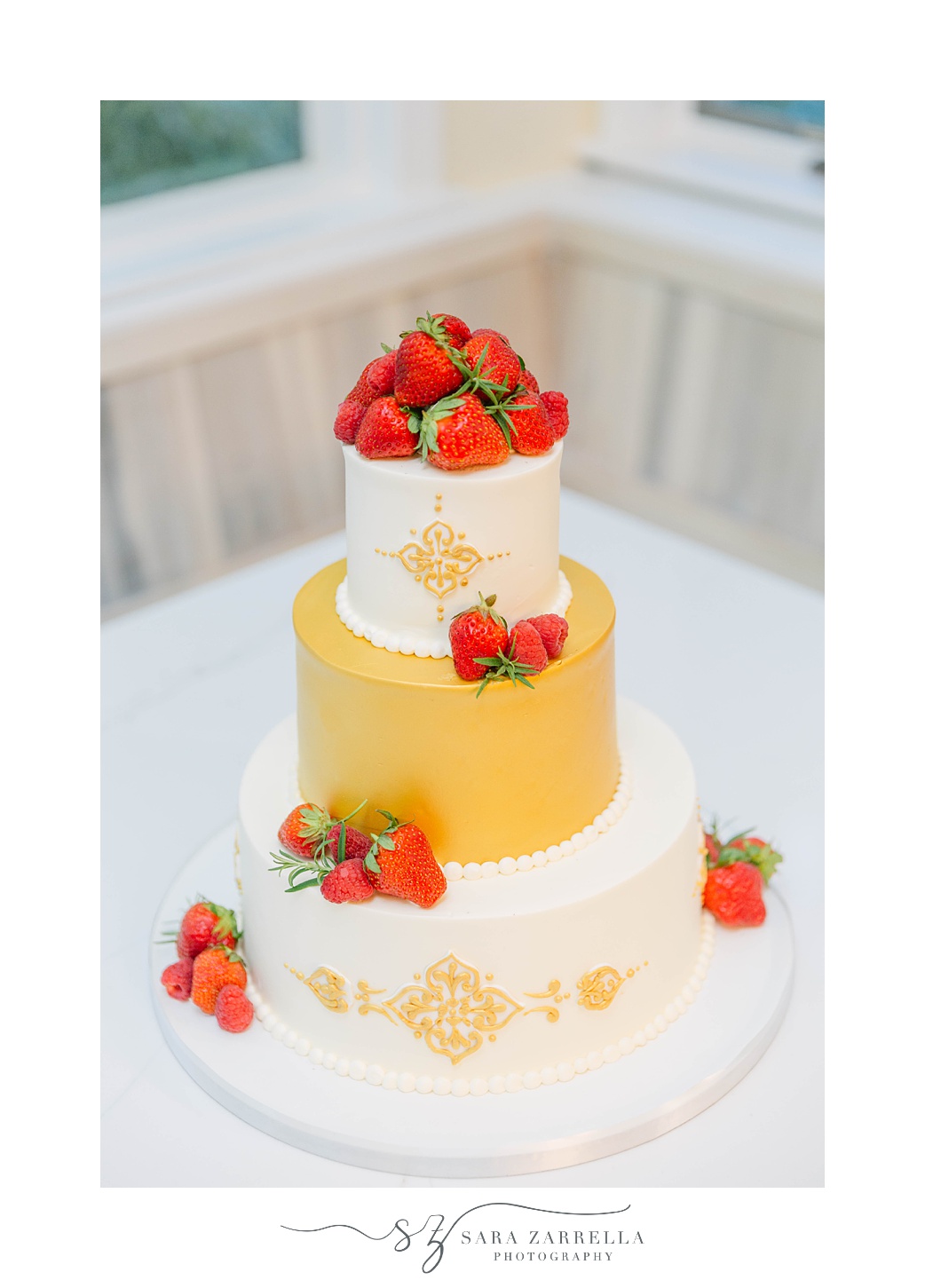 tiered wedding cake with gold and white icing and strawberries 