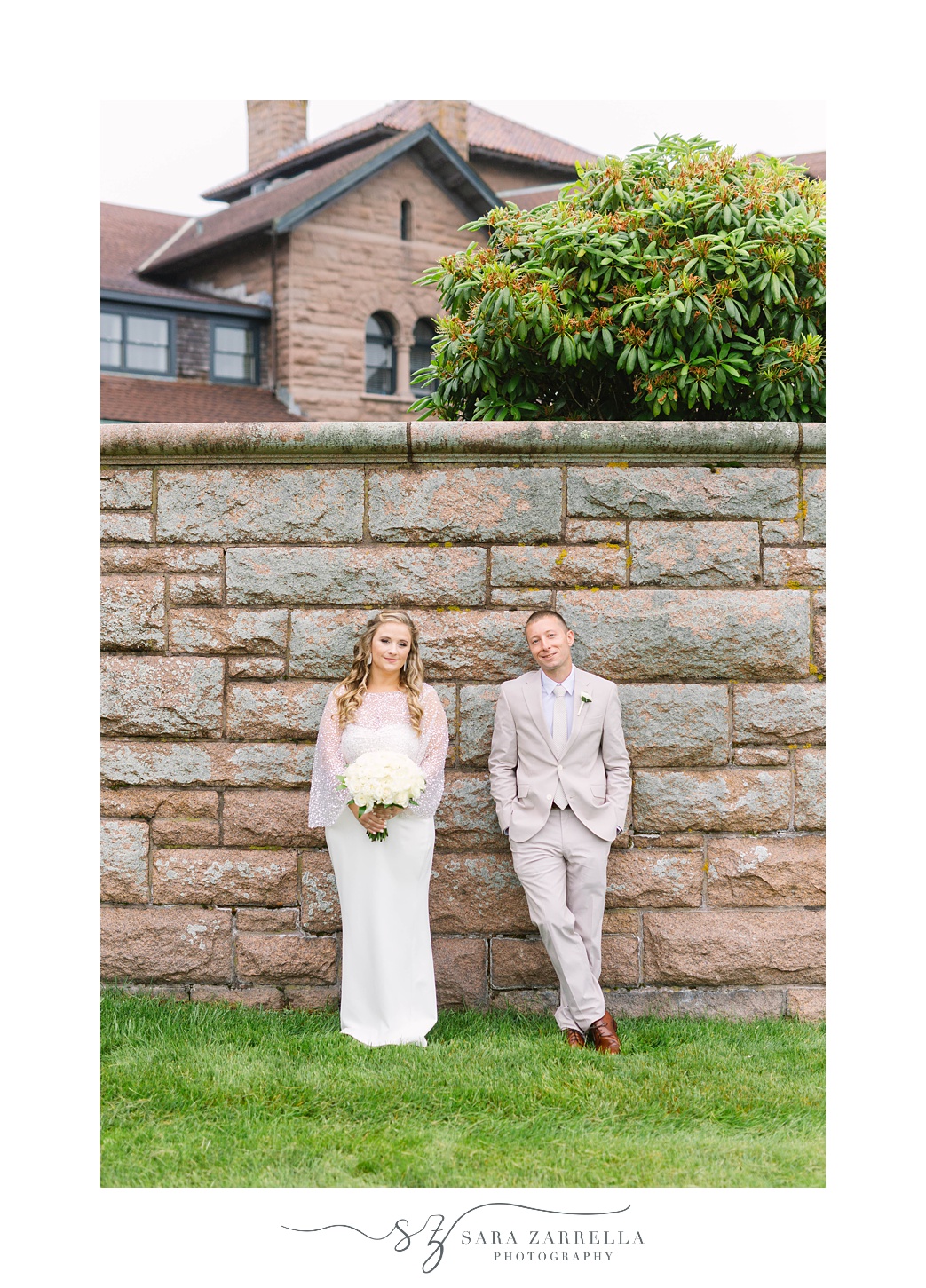 bride and groom lean against stone wall in Newport RI