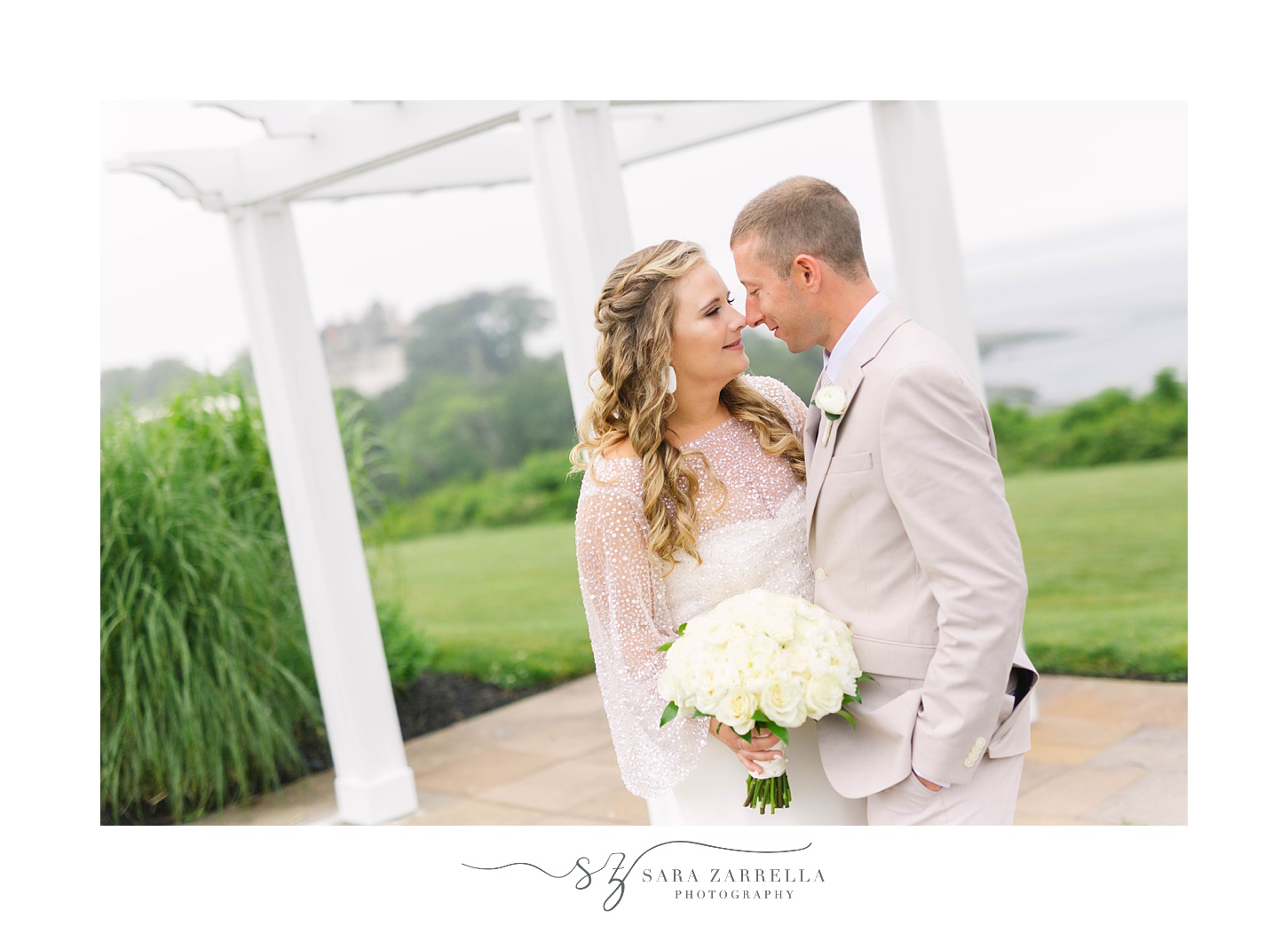 newlyweds pose under white arbor at OceanCliff Hotel