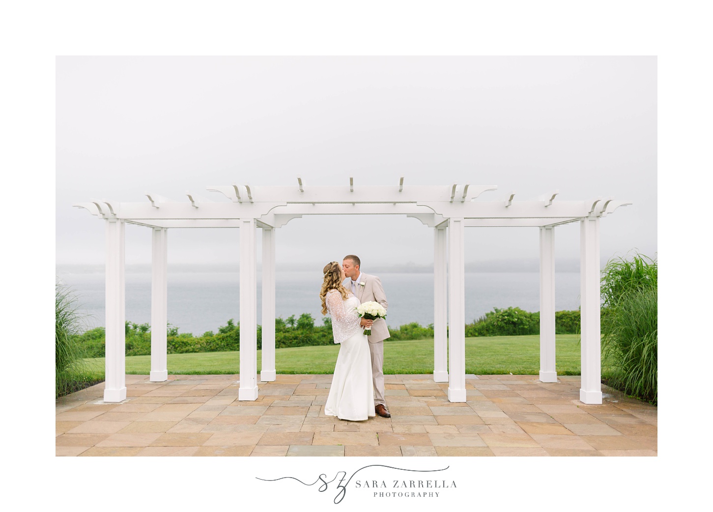 bride and groom kiss under white arbor at OceanCliff Hotel