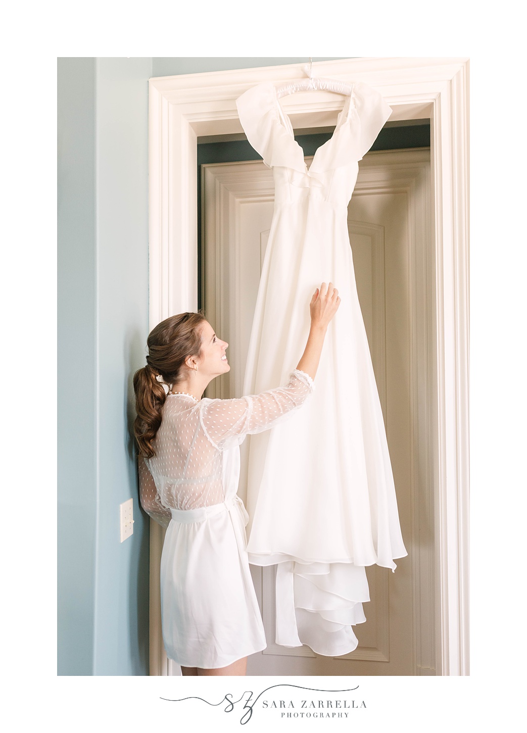 bride looks at wedding gown hanging in bridal suite at The Chanler at Cliff Walk